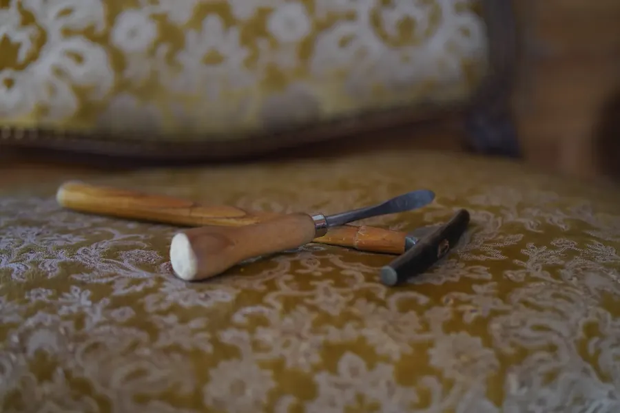 Outils de tapissier posés sur un fauteuil en cours de restauration