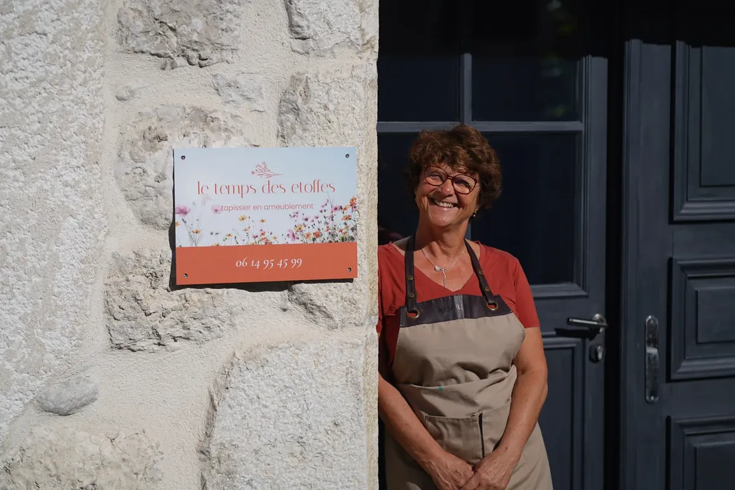 Christine devant la plaque de l'atelier Le Temps des Étoffes, à Chanaz