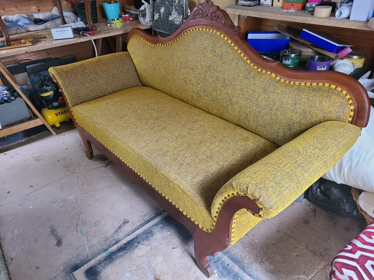 Banquette ancienne en cours de restauration, tissu jaune moutarde, dans l'atelier de tapisserie