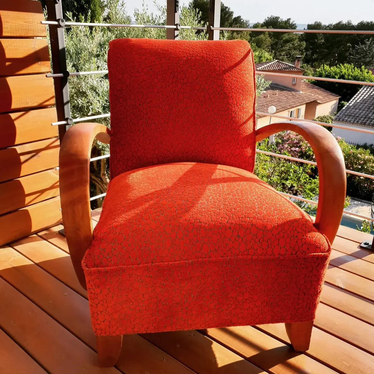 Fauteuil club Art déco aux accoudoirs galbés, tissu graphique orange, sur une terrasse