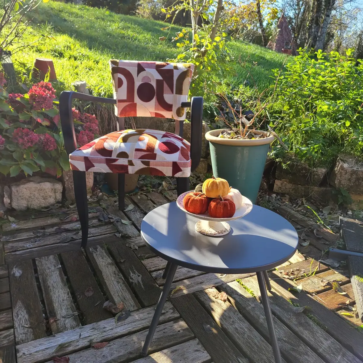 Fauteuil de jardin en tissu graphique rouge et or, sur une terrasse fleurie