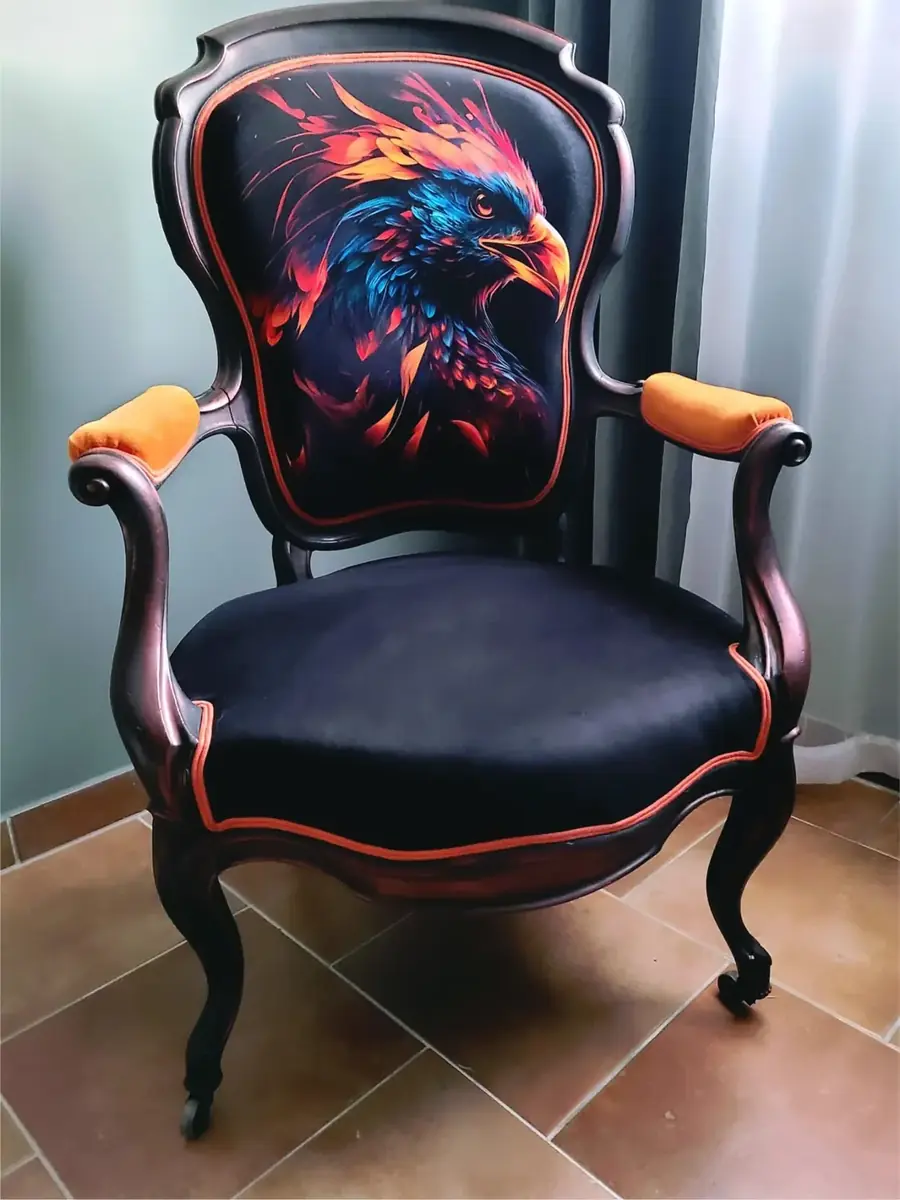 Fauteuil ancien restauré, dossier à motif de tête d'aigle multicolore sur fond noir, accoudoirs en velours orange