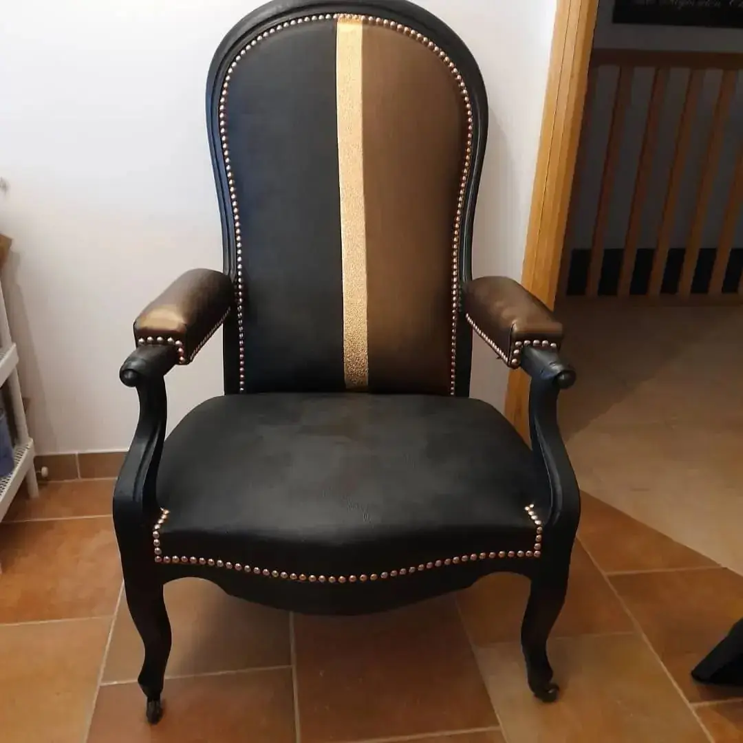 Fauteuil voltaire habillé de simili cuir noir et bande dorée centrale, cloutage doré