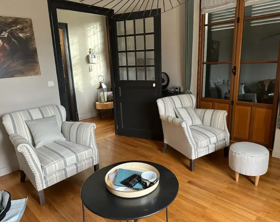 Paire de fauteuils voltaire rayés beige et gris à clous, dans un salon cosy